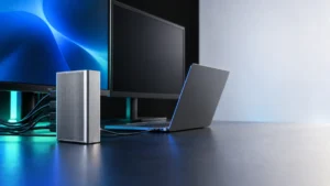 Silver desktop dock beside a Windows laptop and two monitors, with one monitor dark.